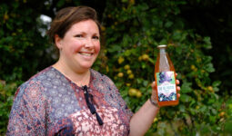 Portrait d'Aurélie Rio avec une bouteille de jus de pomme à la main