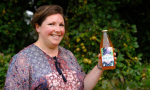 Portrait d'Aurélie Rio avec une bouteille de jus de pomme à la main