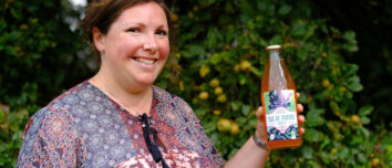Portrait d'Aurélie Rio avec une bouteille de jus de pomme à la main