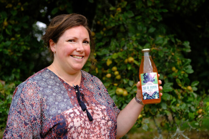 Portrait d'Aurélie Rio avec une bouteille de jus de pomme à la main