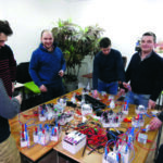 Des hommes autour d'une table avec du matérile d'électricité posé dessus