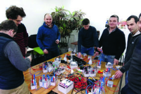 Des hommes autour d'une table avec du matérile d'électricité posé dessus