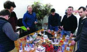 Des hommes autour d'une table avec du matérile d'électricité posé dessus