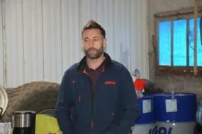 Un homme dans un atelier avec une roue de tracteur derrière