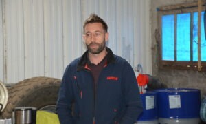 Un homme dans un atelier avec une roue de tracteur derrière