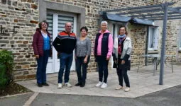 Des personnes devant une maison d'habitation en vieilles pierres