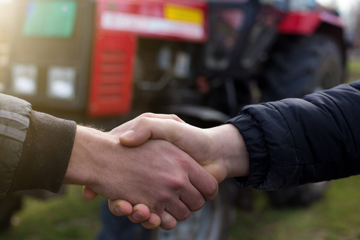 poignée de main devant un tracteur - Illustration Une journée d’échanges à Châteaubourg