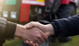 poignée de main devant un tracteur