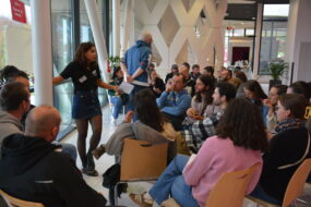 un groupe de personnes face à une exposante sur un salon