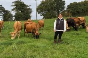 Une éleveuse au milieu de vaches de race Jersiaise au pâturage