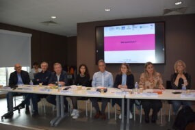 Des personnes à une tribune avec un écran derrère