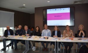 Des personnes à une tribune avec un écran derrère