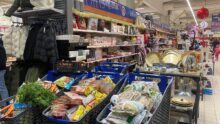 Trois caddy remplis de produits alimentaires dans un magasin de grande distribution