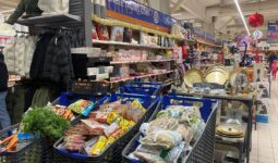 Trois caddy remplis de produits alimentaires dans un magasin de grande distribution