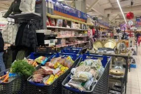 Trois caddy remplis de produits alimentaires dans un magasin de grande distribution