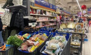 Trois caddy remplis de produits alimentaires dans un magasin de grande distribution