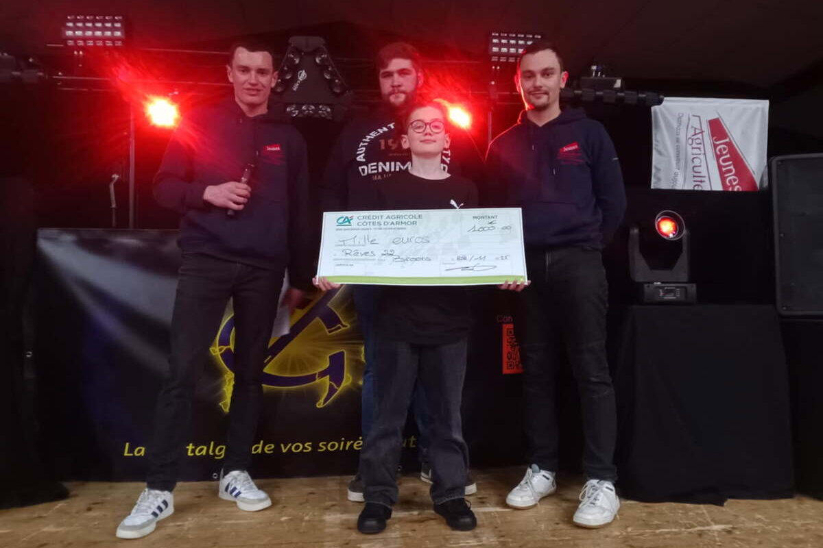 Trois jeunes hommes avec un enfant lors d'une remise de chèque - Illustration Les JA de Caulnes font un don à Rêves 22