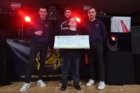 Trois jeunes hommes avec un enfant lors d'une remise de chèque