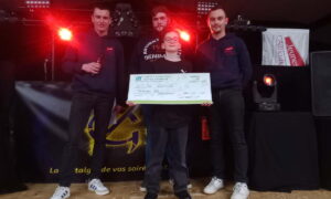 Trois jeunes hommes avec un enfant lors d'une remise de chèque