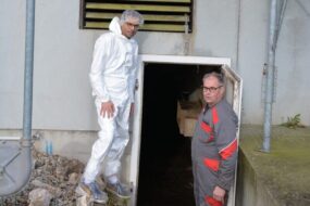 Deux personnes devant le système de chauffage d'une porcherie