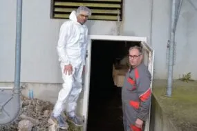 Deux personnes devant le système de chauffage d'une porcherie
