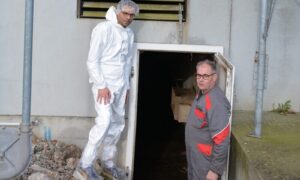 Deux personnes devant le système de chauffage d'une porcherie