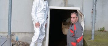 Deux personnes devant le système de chauffage d'une porcherie