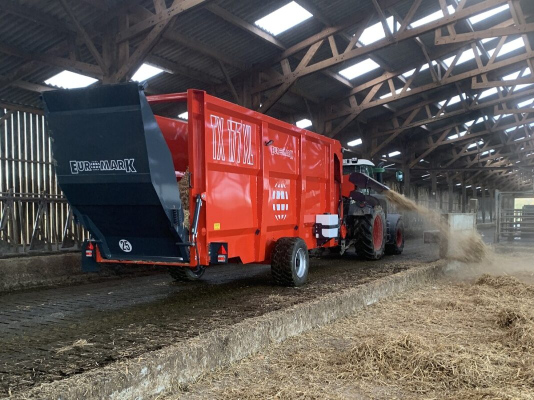 Une pailleuse attelée à un tracteur en train de projeter de la paille sur le côté