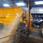 Une pailleuse attelée à un tracteur en train de projeter de la paille sur le côté