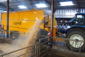 Une pailleuse attelée à un tracteur en train de projeter de la paille sur le côté