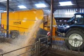 Une pailleuse attelée à un tracteur en train de projeter de la paille sur le côté
