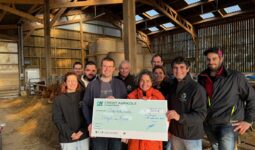 Des personnes dans une étable avec un imense chèque dans les mains