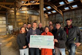 Des personnes dans une étable avec un imense chèque dans les mains