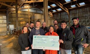 Des personnes dans une étable avec un imense chèque dans les mains