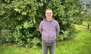 Un homme avec les bras dans le dos dans un jardin