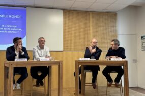 Qautre personnes à une tribune devant un grand écran