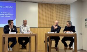 Qautre personnes à une tribune devant un grand écran