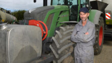 Un homme avec les bras croisés pose devant son tracteur