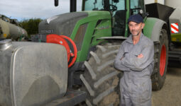 Un homme avec les bras croisés pose devant son tracteur