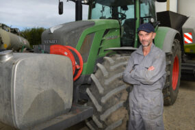 Un homme avec les bras croisés pose devant son tracteur