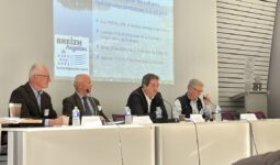 Des personnes à une tribune avec un grand écran derrière