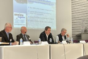 Des personnes à une tribune avec un grand écran derrière