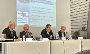 Des personnes à une tribune avec un grand écran derrière