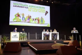 Des personnes sur une scène à une tribune avec un écran géant derrière