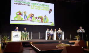 Des personnes sur une scène à une tribune avec un écran géant derrière