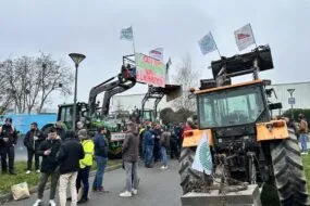 Des manifestants avec des drapeaux et des pancartes accrochés sur des tracteurs