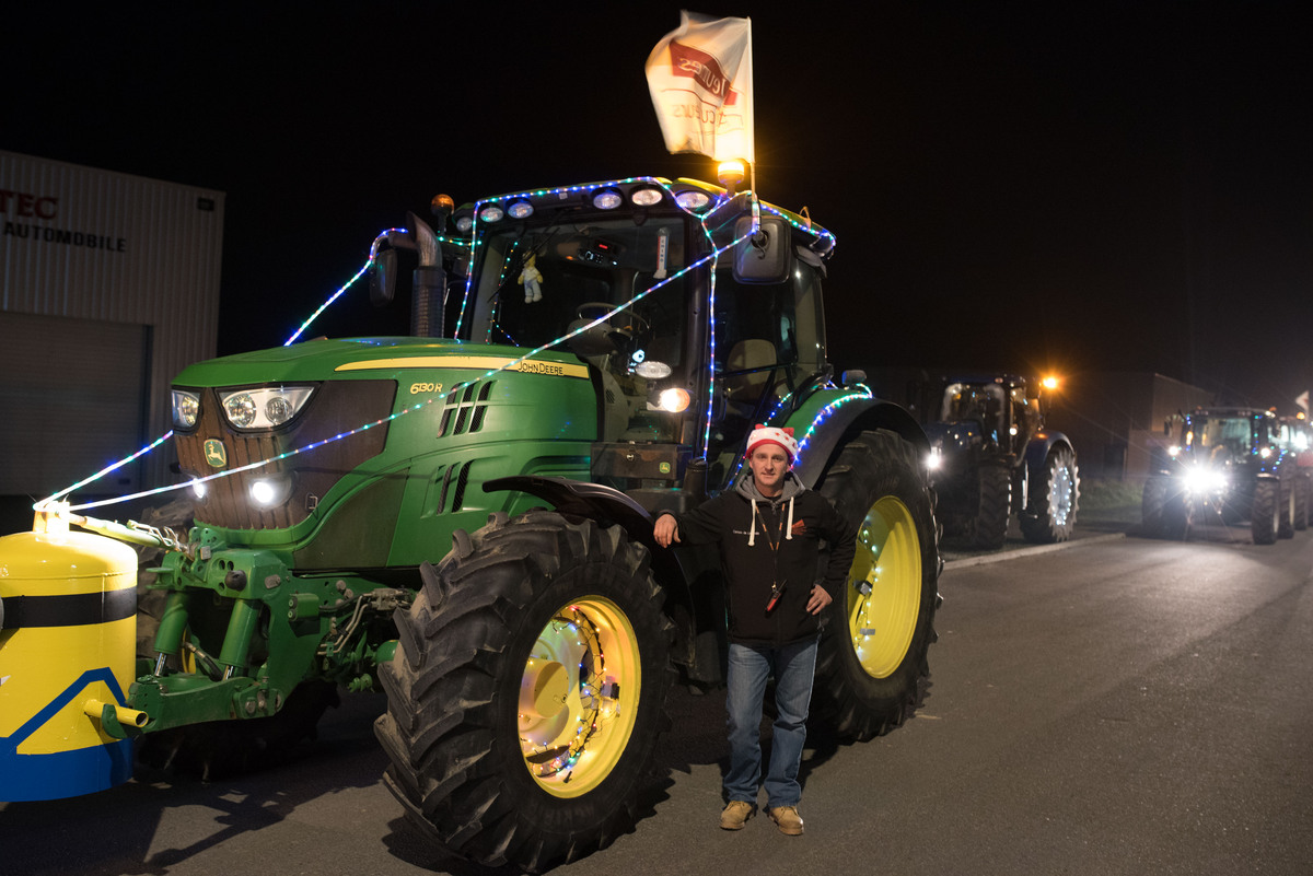 Un jeune agriculteur avec un bonnet de Noël devant un tracteur vert de marque John Deere - Illustration Les JA toujours à la parade