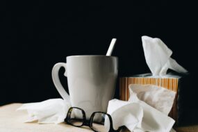 Un mug avec une cuillère, une paire de lunettes et des mouchoirs en papier sur une table