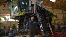 Un homme devant une moissonneuse-batteuse démontée pour effectuer l'entretien