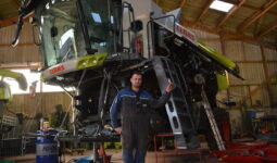 Un homme devant une moissonneuse-batteuse démontée pour effectuer l'entretien